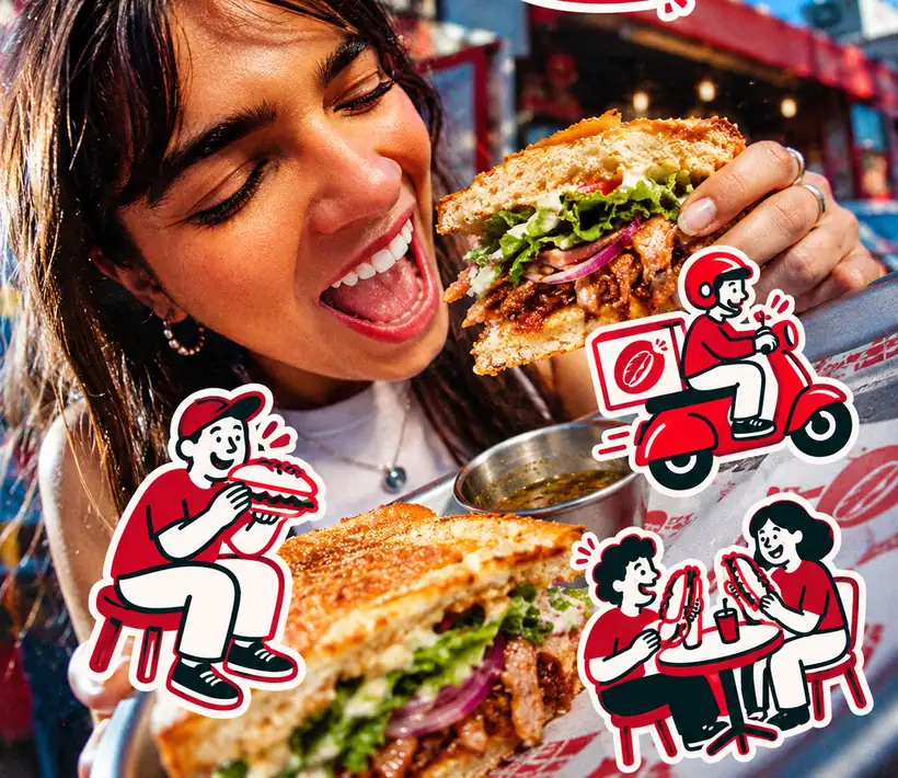 Chica a punto de morder un sándwich de La Antojería en San Pablo Anicano, Puebla, rodeada de las ilustraciones de la marca